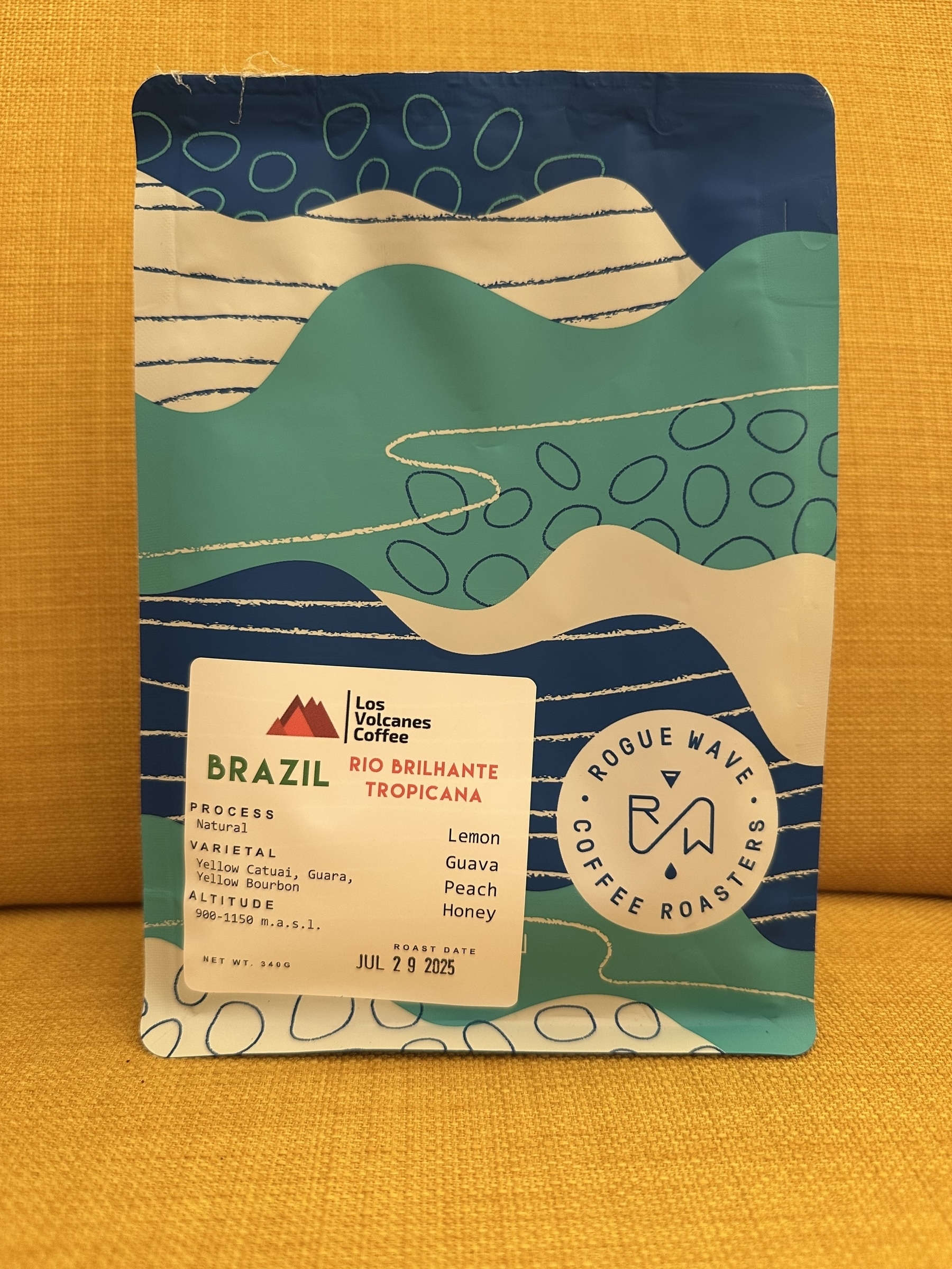 A vibrant coffee package from Rogue Wave Coffee Roasters highlights its Brazilian origin and flavor notes of lemon, guava, peach, and honey.