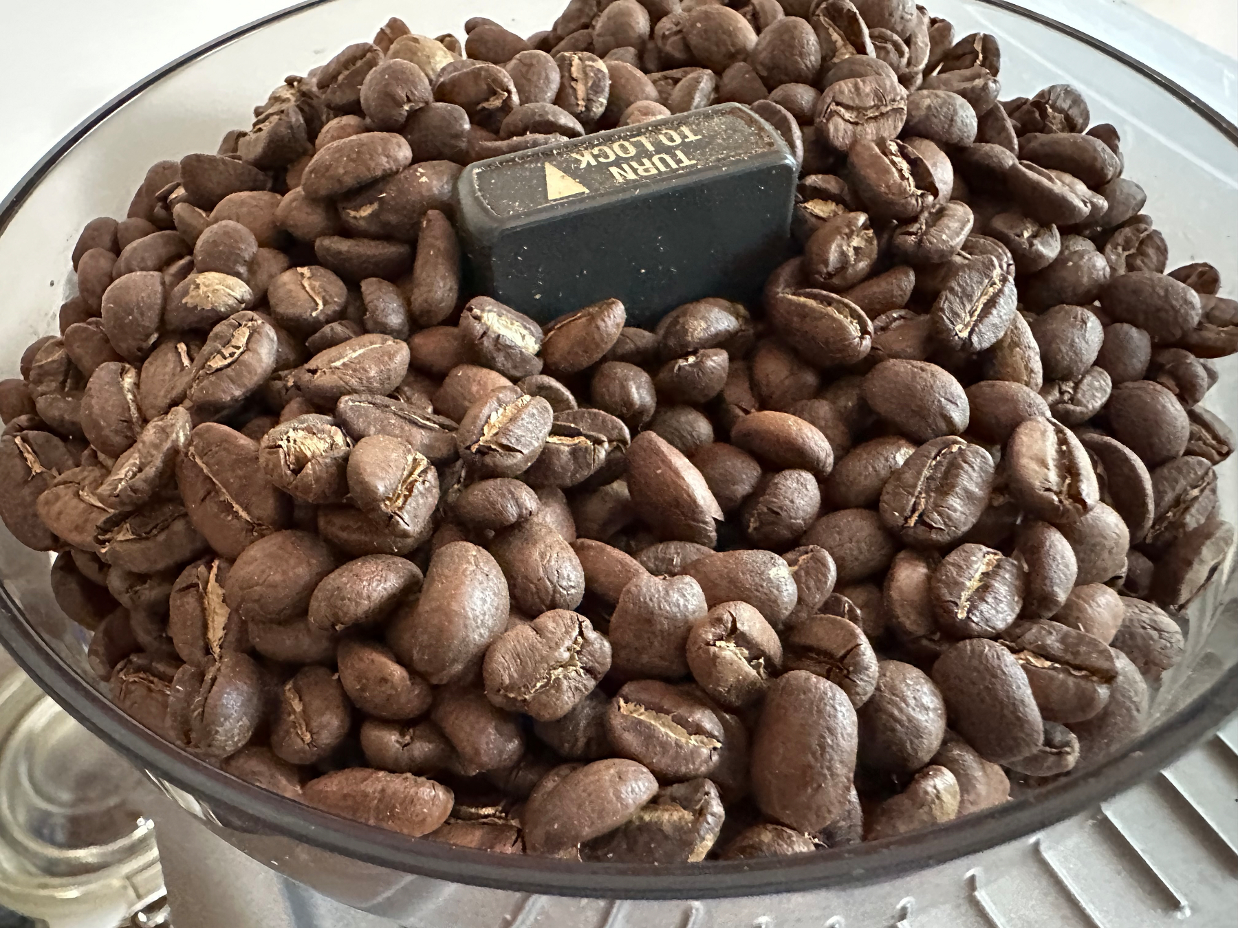 A container filled with whole coffee beans surrounds a central locking mechanism.