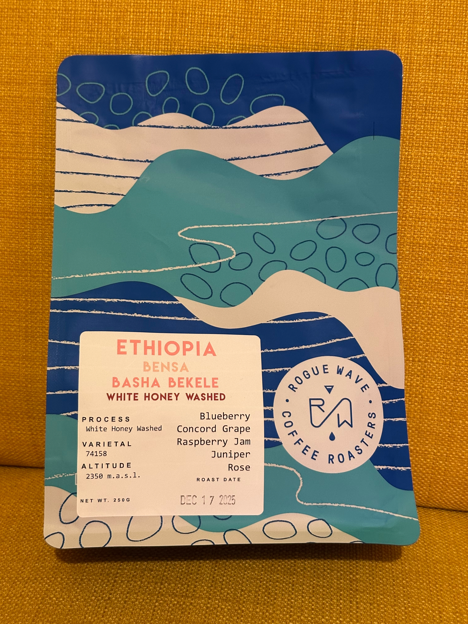 A colorful coffee packaging from Rogue Wave Coffee Roasters details a white honey washed Ethiopian Bensa Basha Bekele with flavor notes of blueberry, Concord grape, raspberry jam, and juniper.