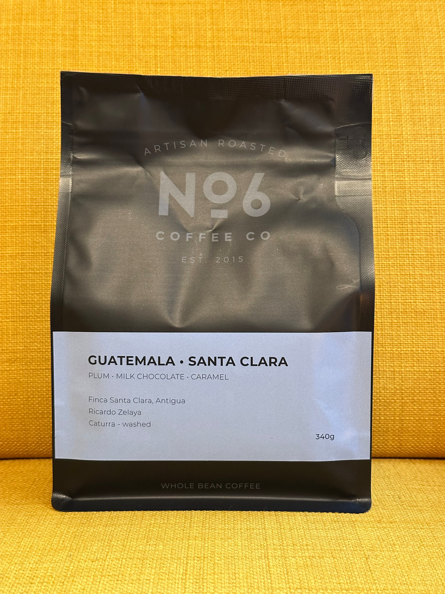 A black and white bag of No6 Coffee Co artisan roasted whole bean coffee from Guatemala, Santa Clara, featuring flavor notes of plum, milk chocolate, and caramel, weighing 340 grams.