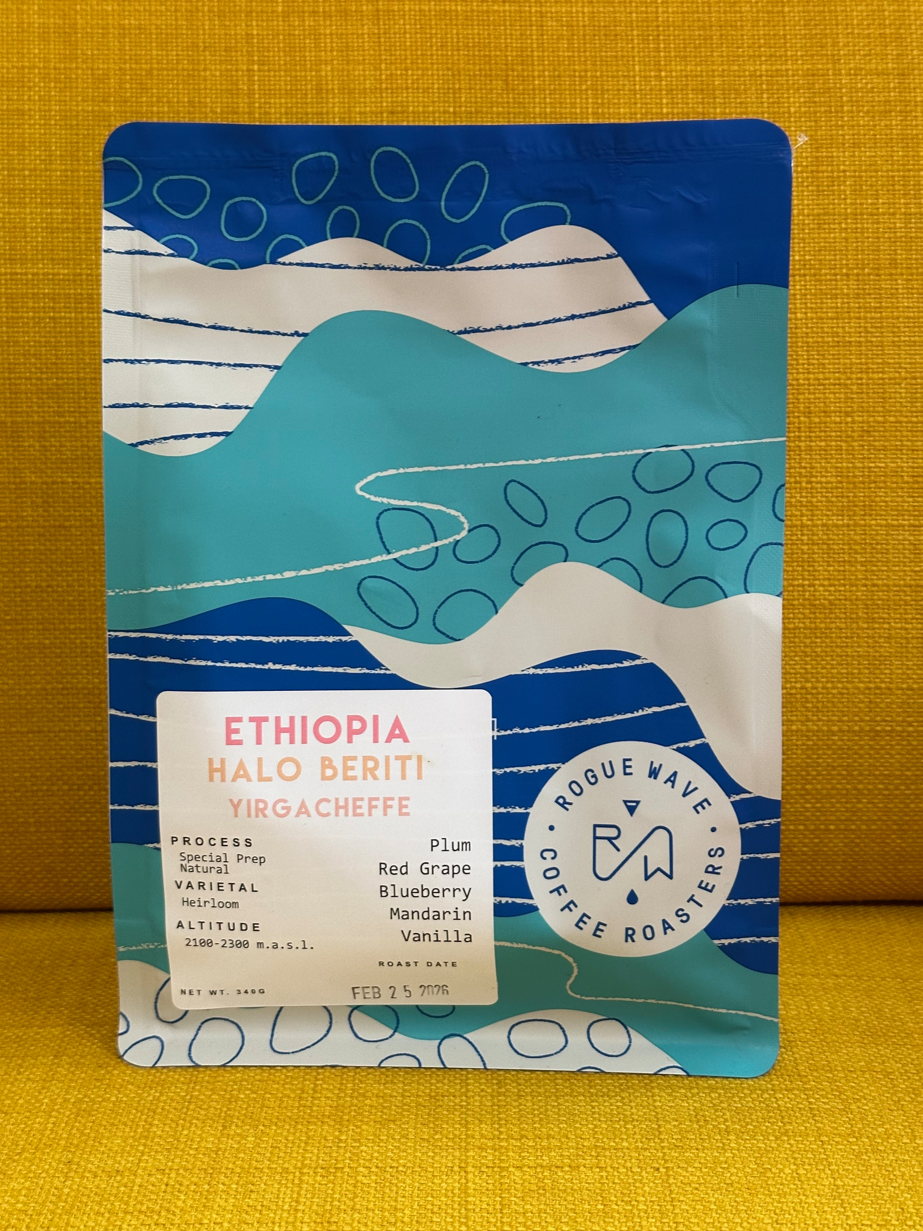 A colorful coffee bag labeled Ethiopia Halo Beriti Yirgacheffe from Rogue Wave Coffee Roasters features tasting notes of plum, red grape, blueberry, mandarin, and vanilla.