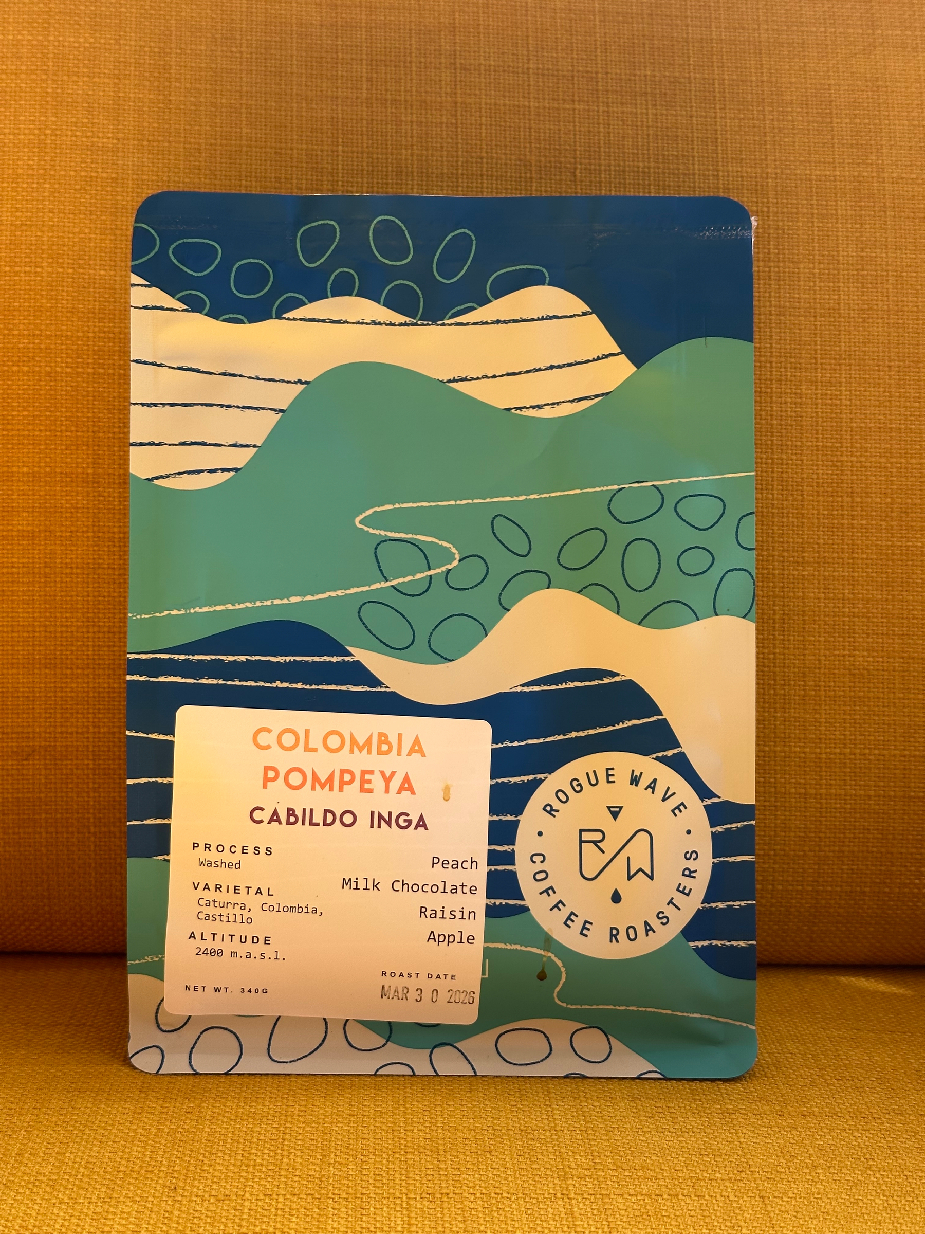 A colorful package of Rogue Wave Coffee Roasters featuring Colombia Pompeya with tasting notes of peach, milk chocolate, raisin, and apple.